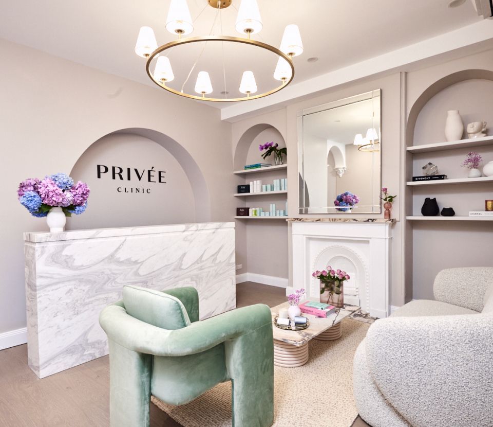 Reception area of a clinic, with marble desk, soft seating, and a modern chandelier.