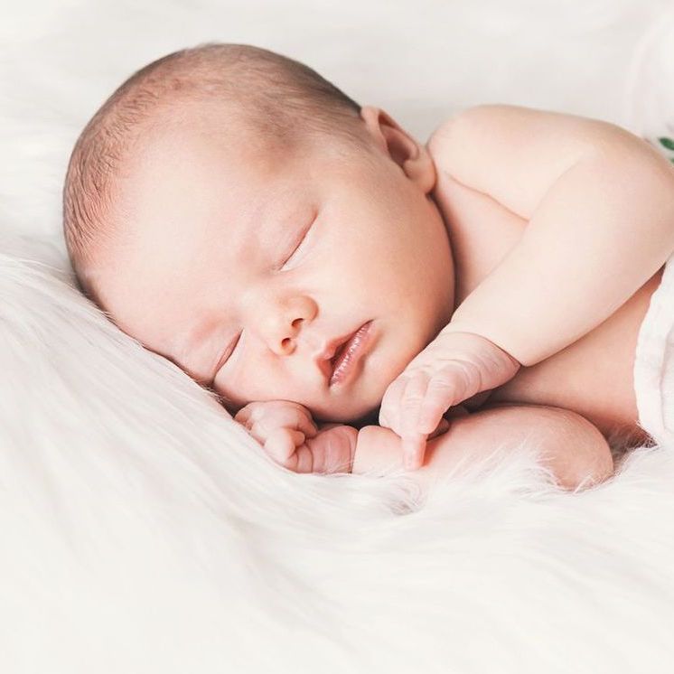 Sleeping newborn baby in a wrap on white blanket