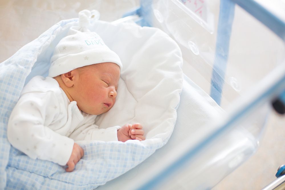 Newborn baby laying in crib in prenatal hospital