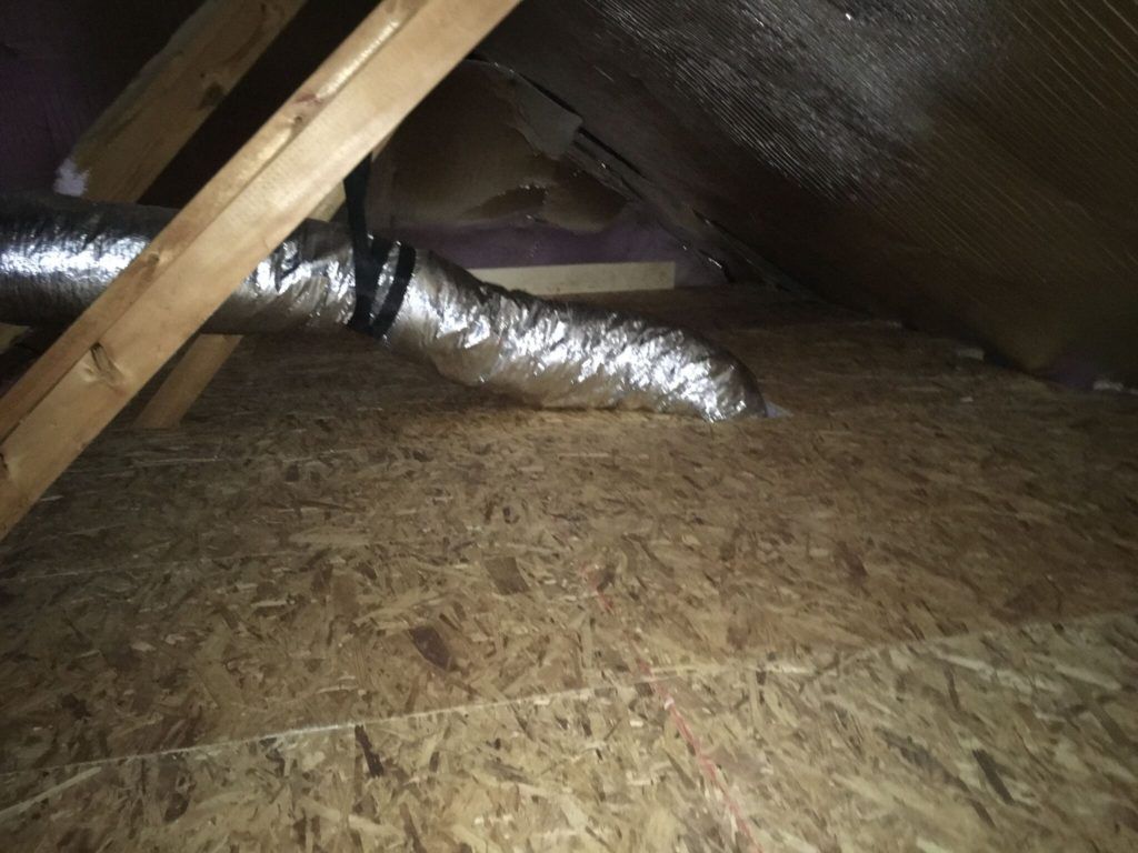 Attic interior with exposed wood beams, ductwork, and plywood flooring.