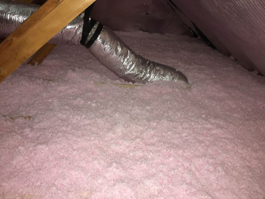 Pink insulation in an attic, with an air duct and wooden beams.