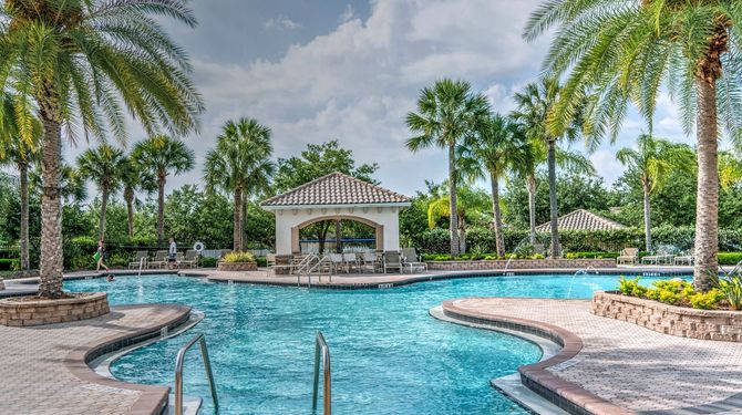 Tropical resort pool with palm trees, lounge chairs, and a shaded gazebo beside the water