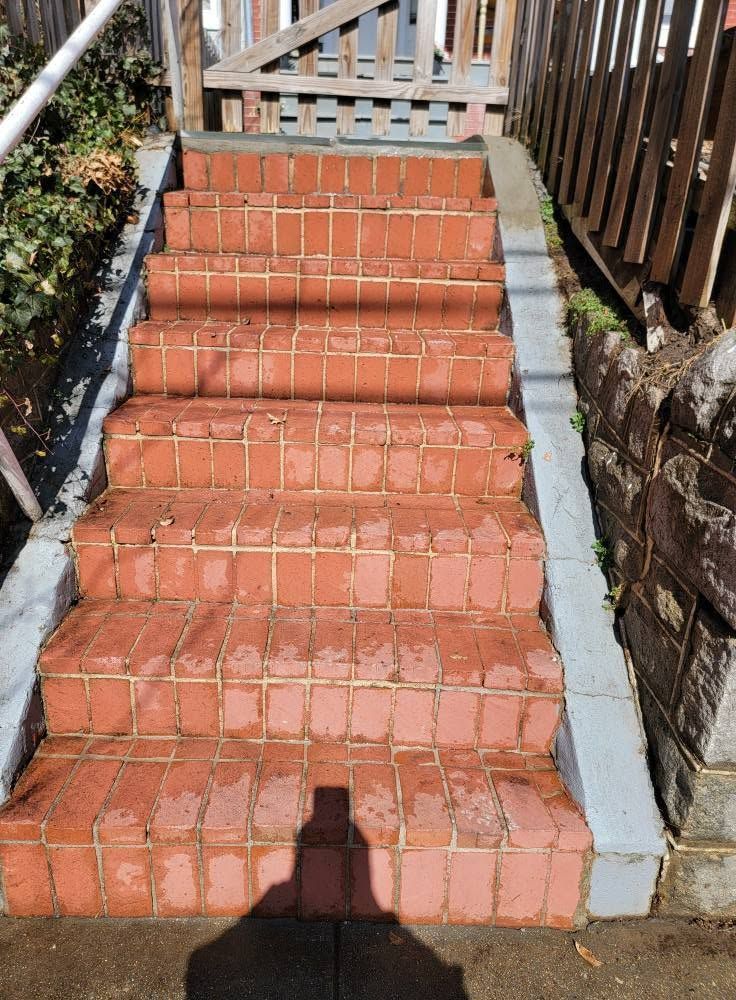 Red brick outdoor staircase with concrete sides and wooden railings, seen from above.