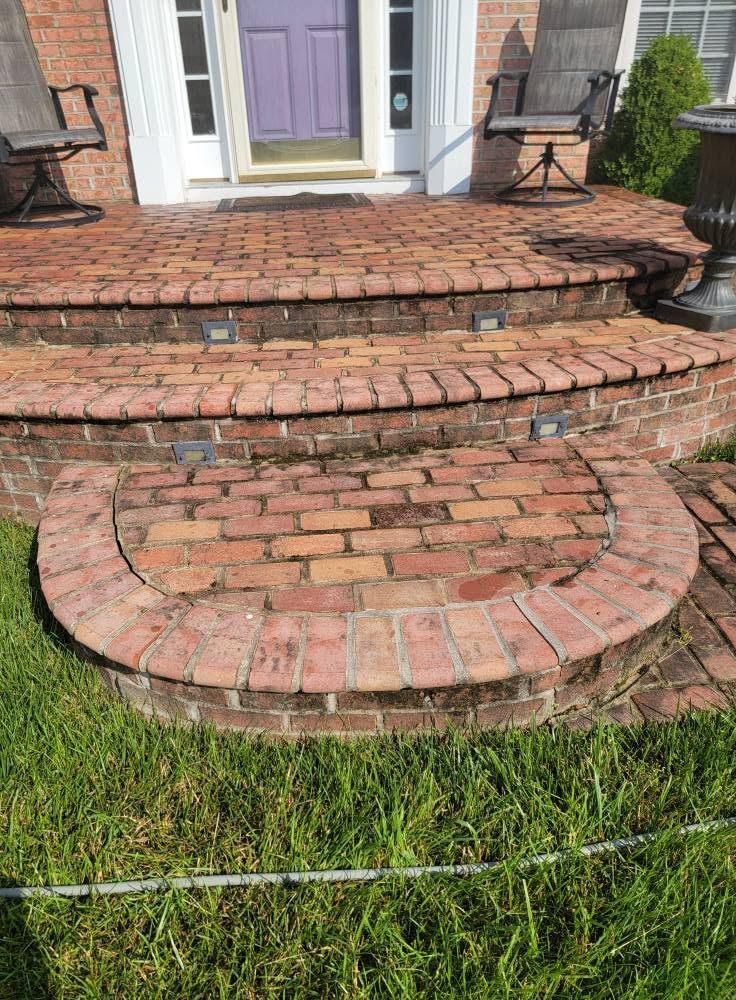Brick front steps with curved lower landing leading to a purple front door and white columns