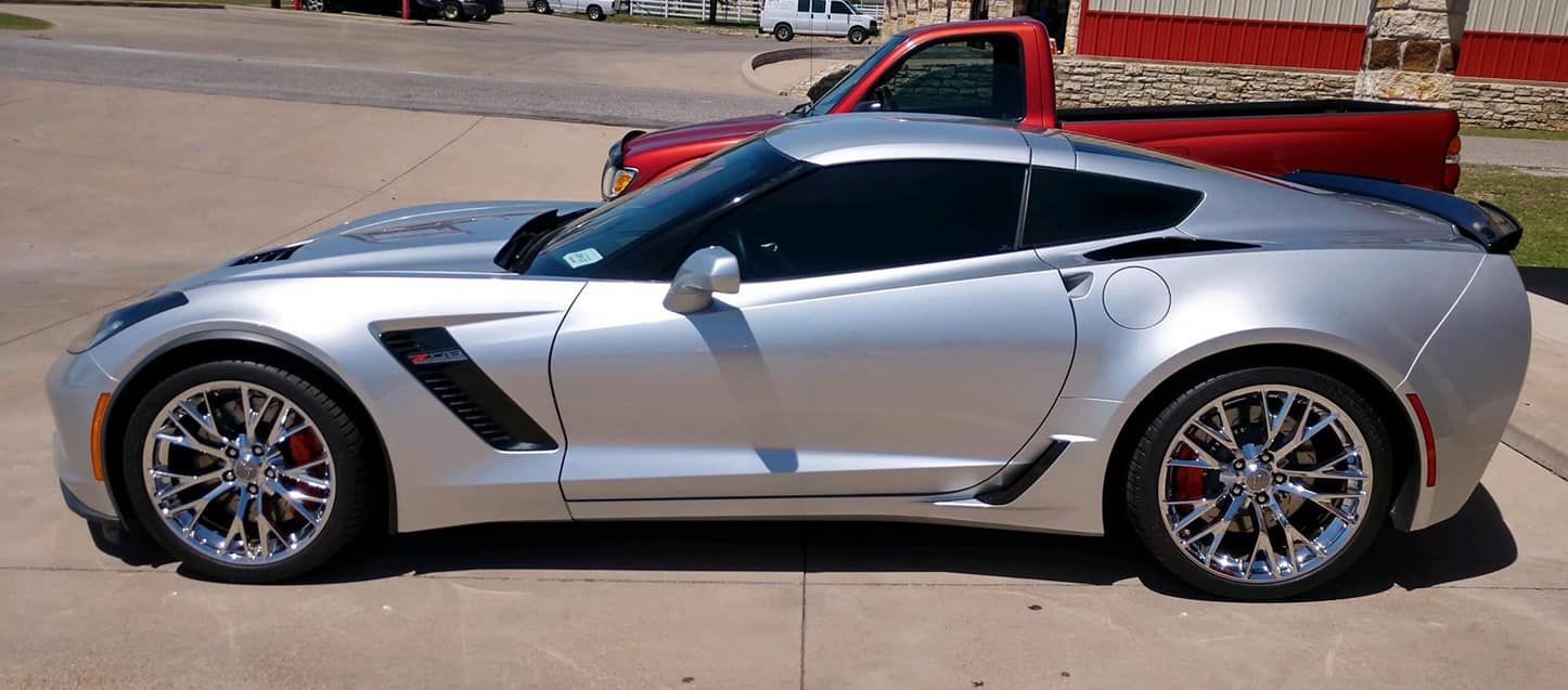 Silver sports car with chrome rims, tinted windows, and red brake calipers, parked.