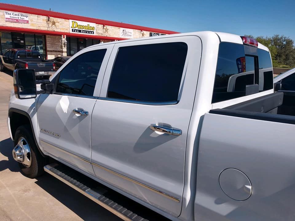 White pickup truck with tinted windows parked near a building on a sunny day.