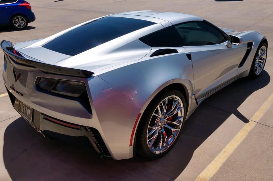 Silver Corvette sports car, rear view, parked in a parking lot.