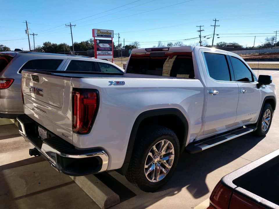 White GMC Sierra pickup truck parked outside a business on a sunny day.