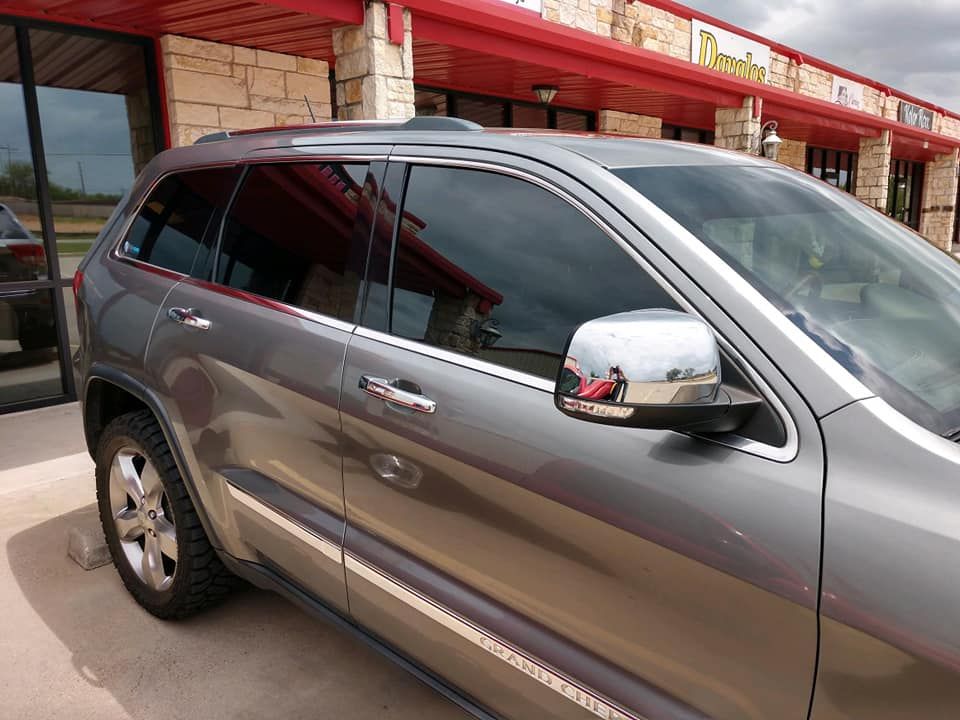 Gray Jeep SUV parked in front of a building with red trim.