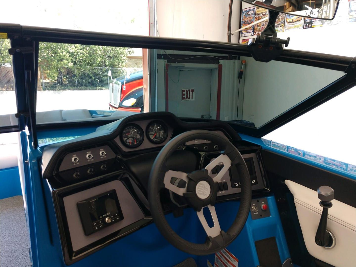 Boat dashboard with steering wheel, gauges, and controls, featuring blue and black accents.
