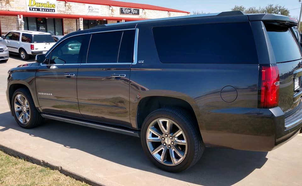 Dark gray SUV parked outside a building with tinted windows.
