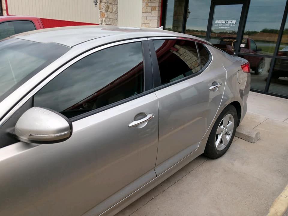 Silver sedan parked outside a building with tinted windows.