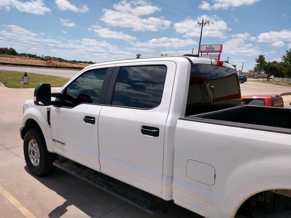 White pickup truck with tinted windows parked on concrete. Cloudy sky in the background.