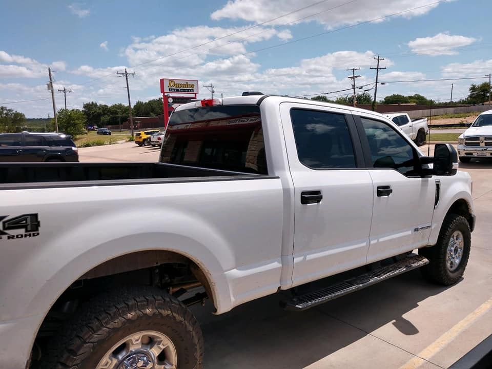 White Ford pickup truck with black trim parked outside a business on a sunny day.