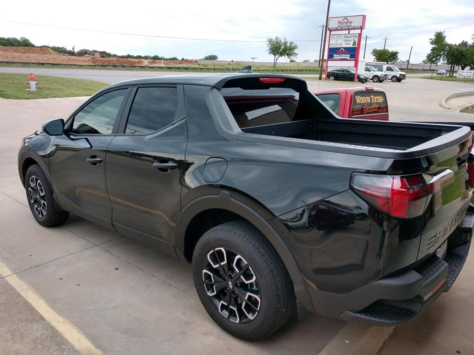 Black Hyundai Santa Cruz pickup truck parked on pavement.