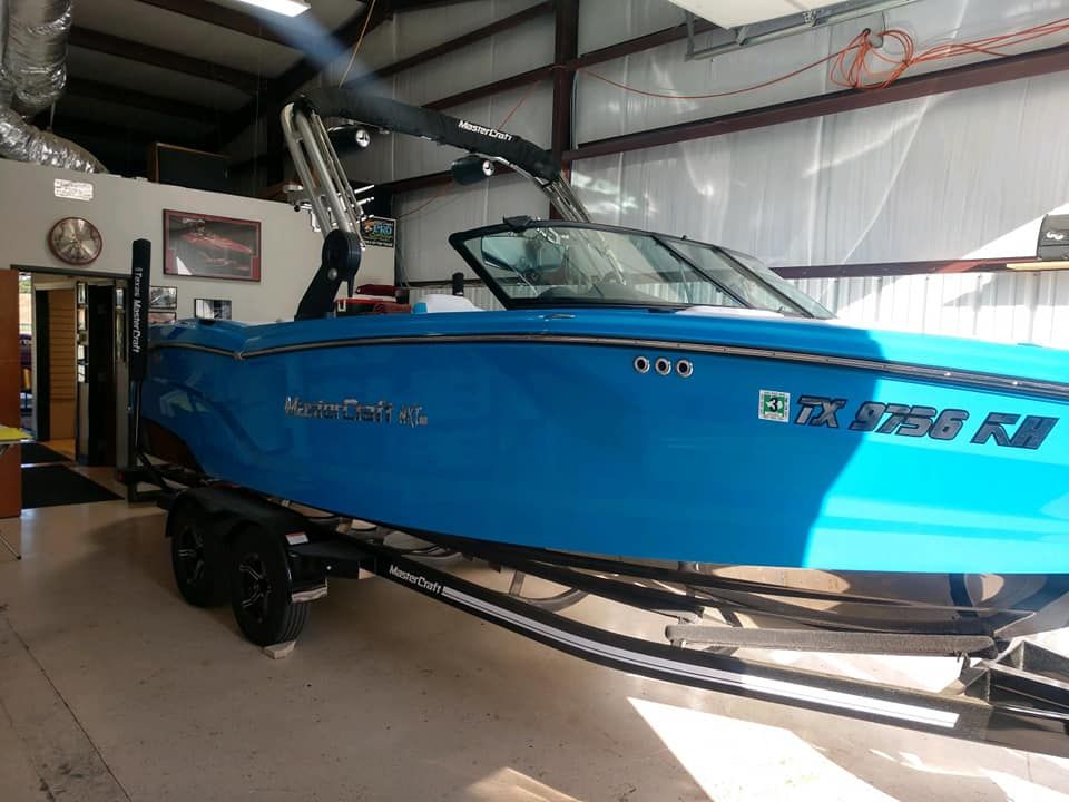 Blue and black motorboat on a trailer inside a building with large garage doors.