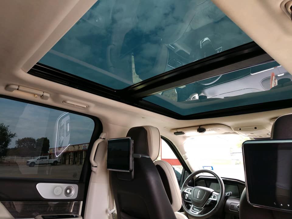 Interior of a Lincoln Navigator with a large sunroof. Black and tan leather seats, steering wheel visible.
