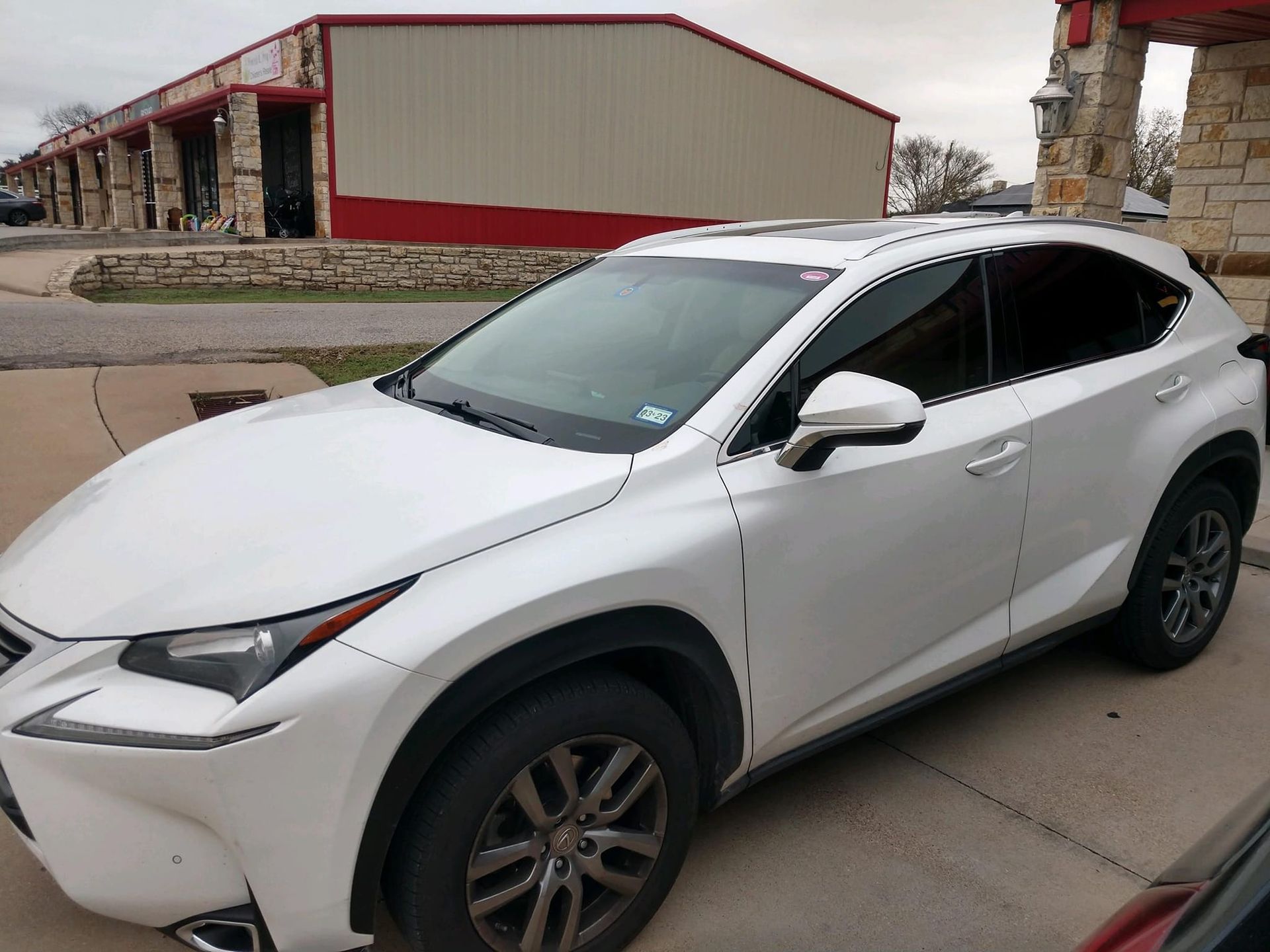 White Lexus SUV parked in front of a building with red and tan facade.