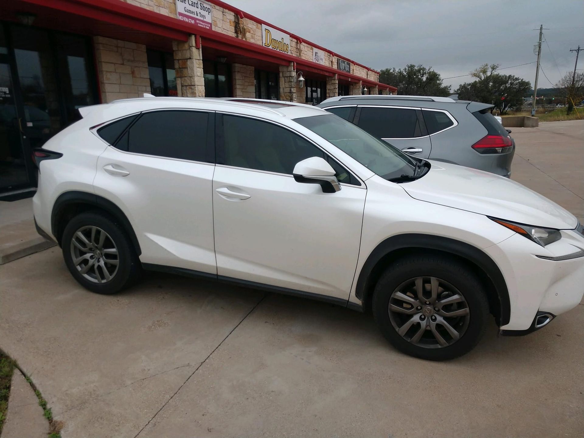 White Lexus SUV parked outside a brick building with tinted windows.