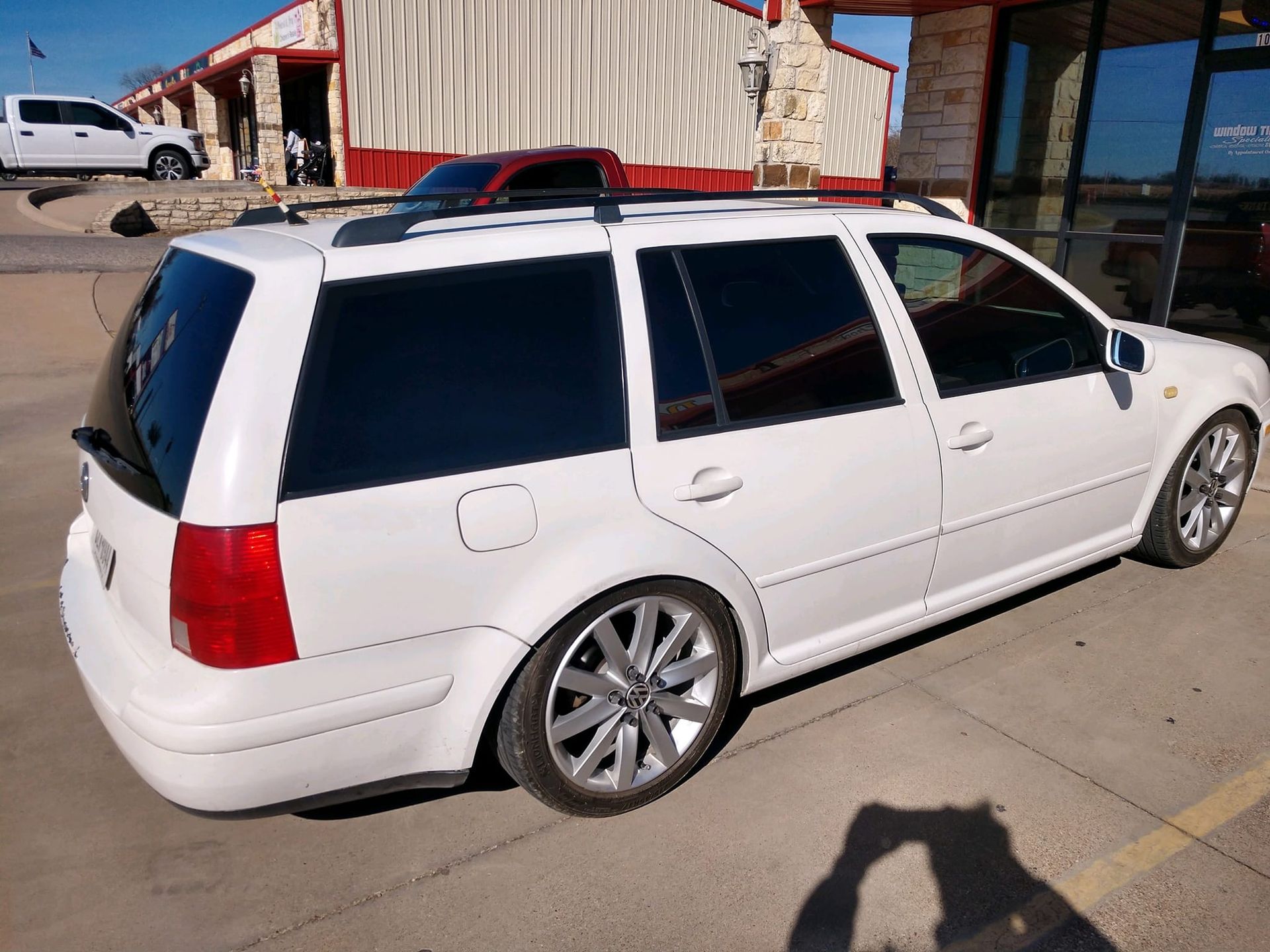White station wagon with tinted windows parked outside a building.