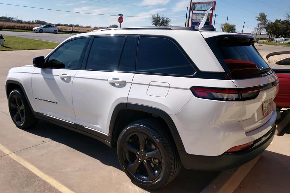 White SUV with black wheels and tinted windows parked on a sunny day.