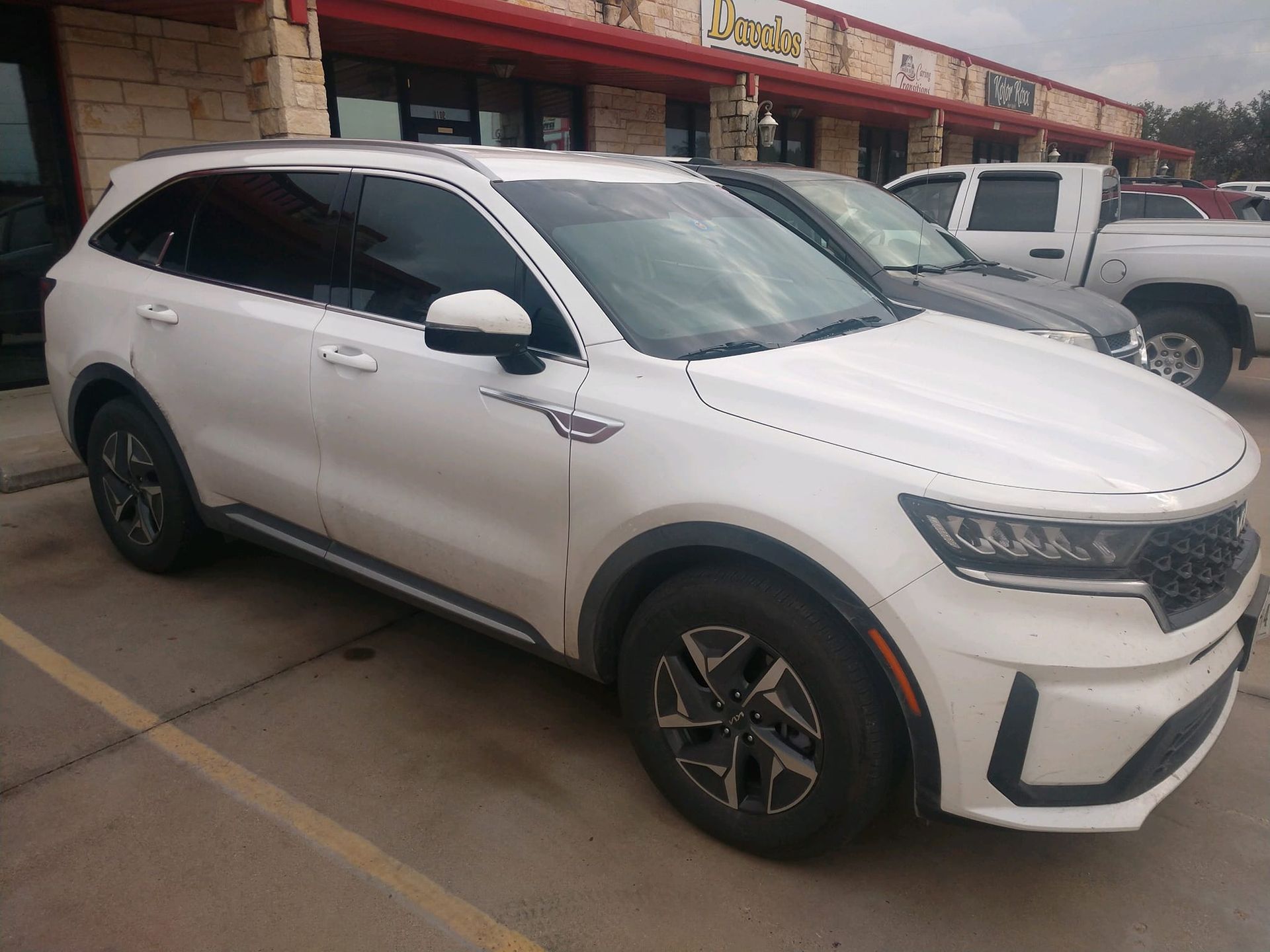 White Kia Sorento SUV parked in front of a building.