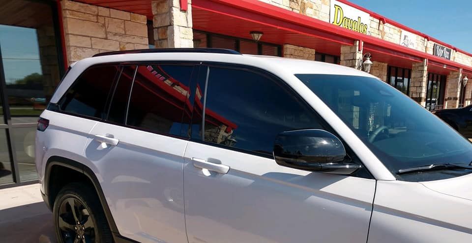 White SUV with tinted windows parked in front of a building with a red awning.