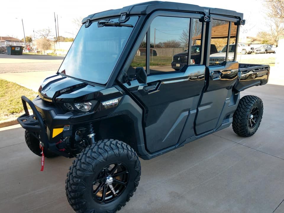 Black off-road utility vehicle with a full cab, large tires, and a front bumper, parked on concrete.