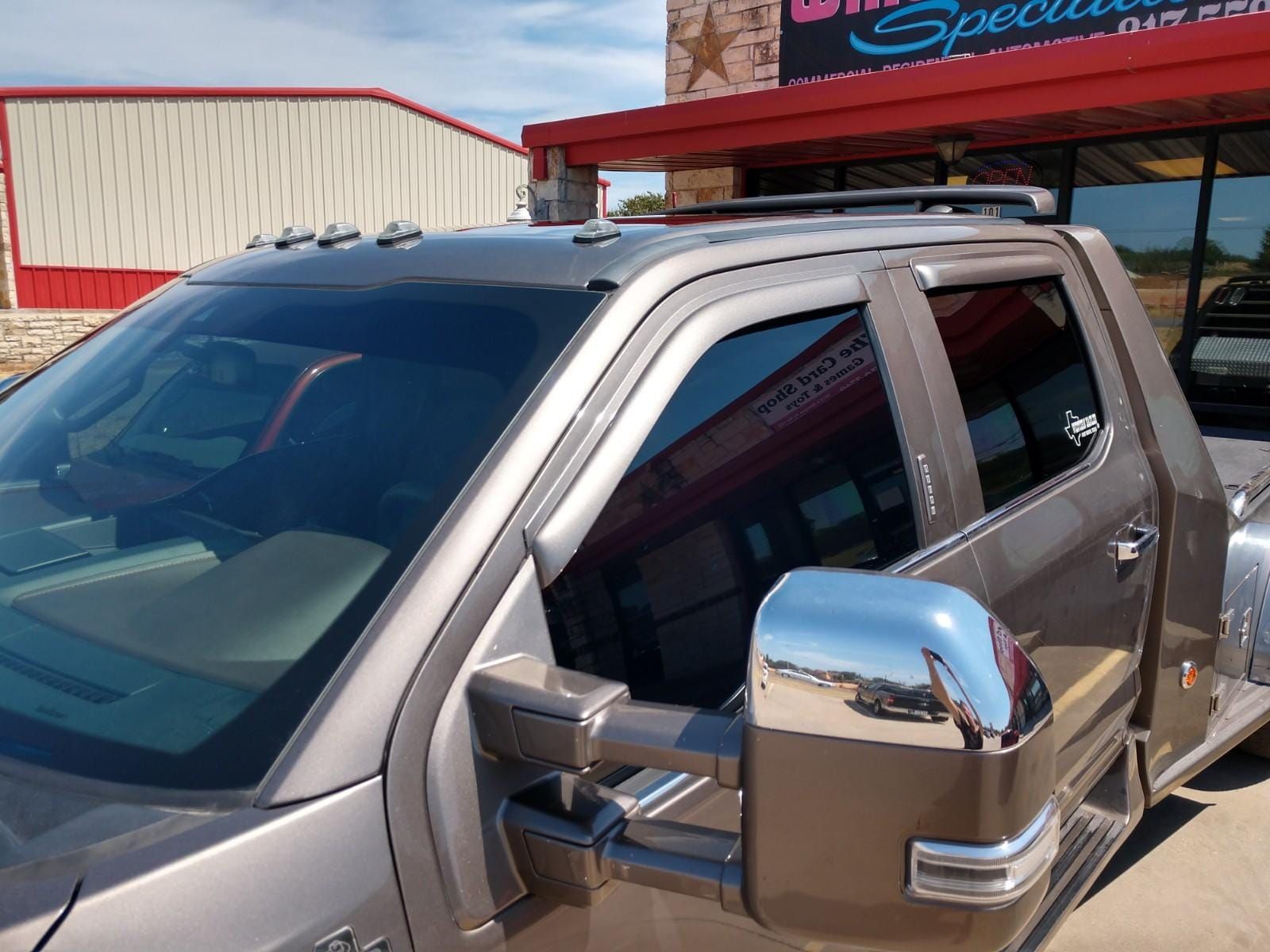 Tan truck with tinted windows, chrome mirrors, parked outside a building with red accents.