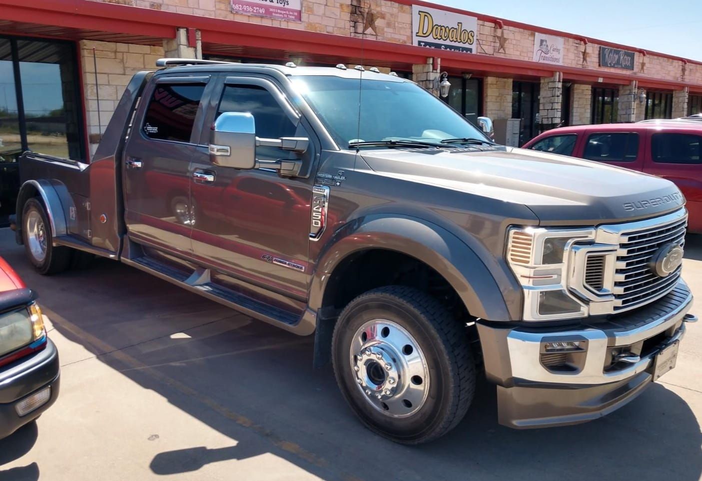 Large gray Ford truck with custom bed in front of a strip mall.