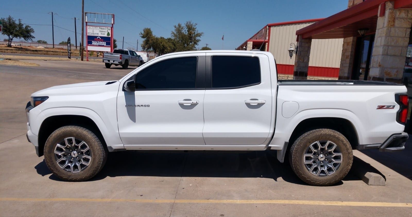 White pickup truck parked outside a building. Dark tinted windows, off-road tires, and Z71 logo.