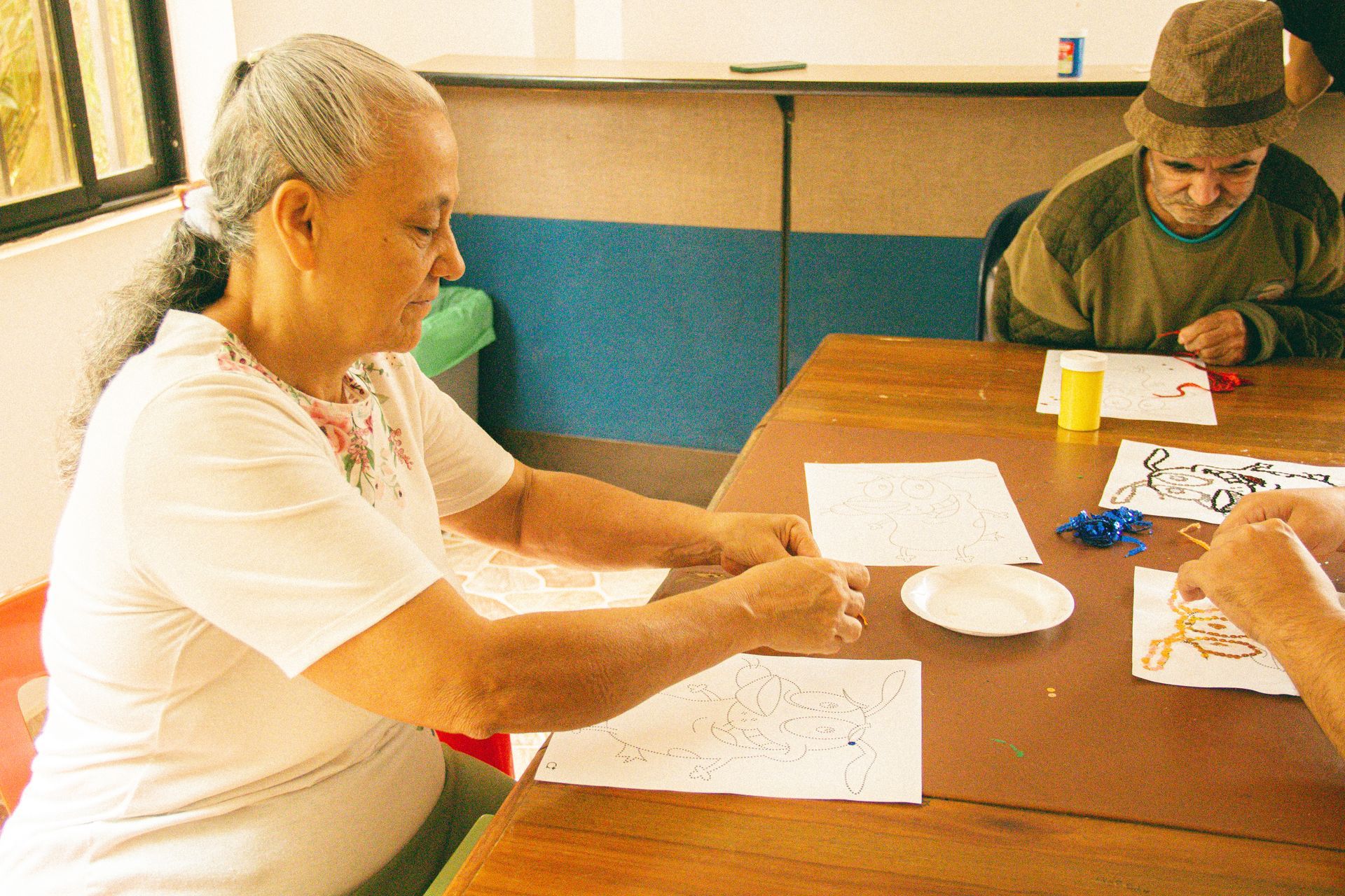 Dos personas están sentadas a una mesa revisando documentos en una habitación luminosa.