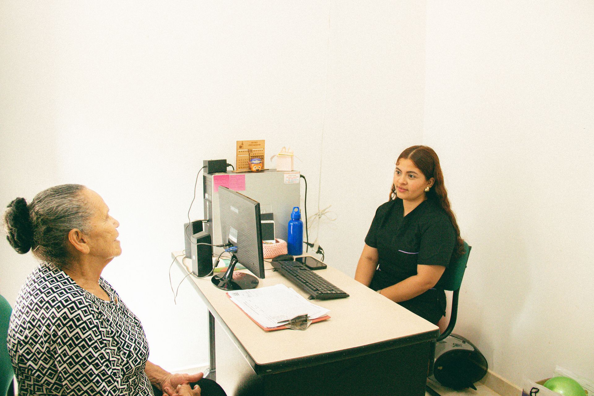 Dos mujeres conversando frente a frente en una pequeña oficina.