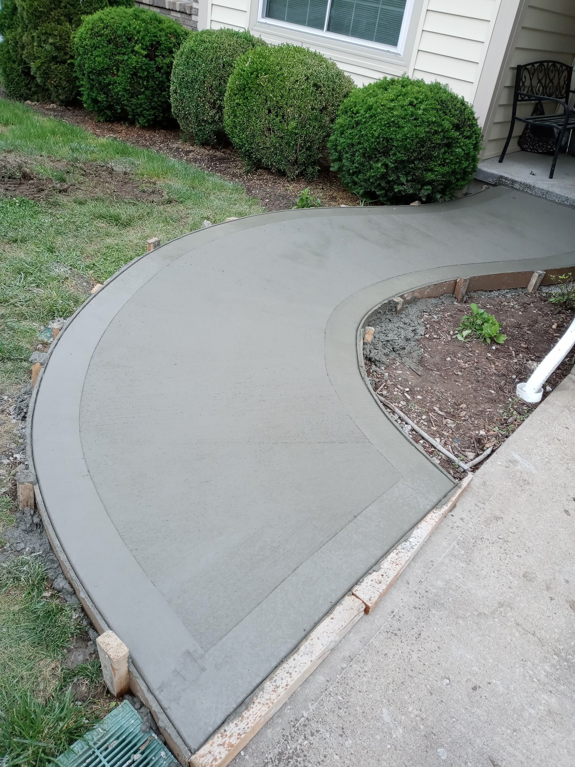 A concrete walkway is being built in front of a house.