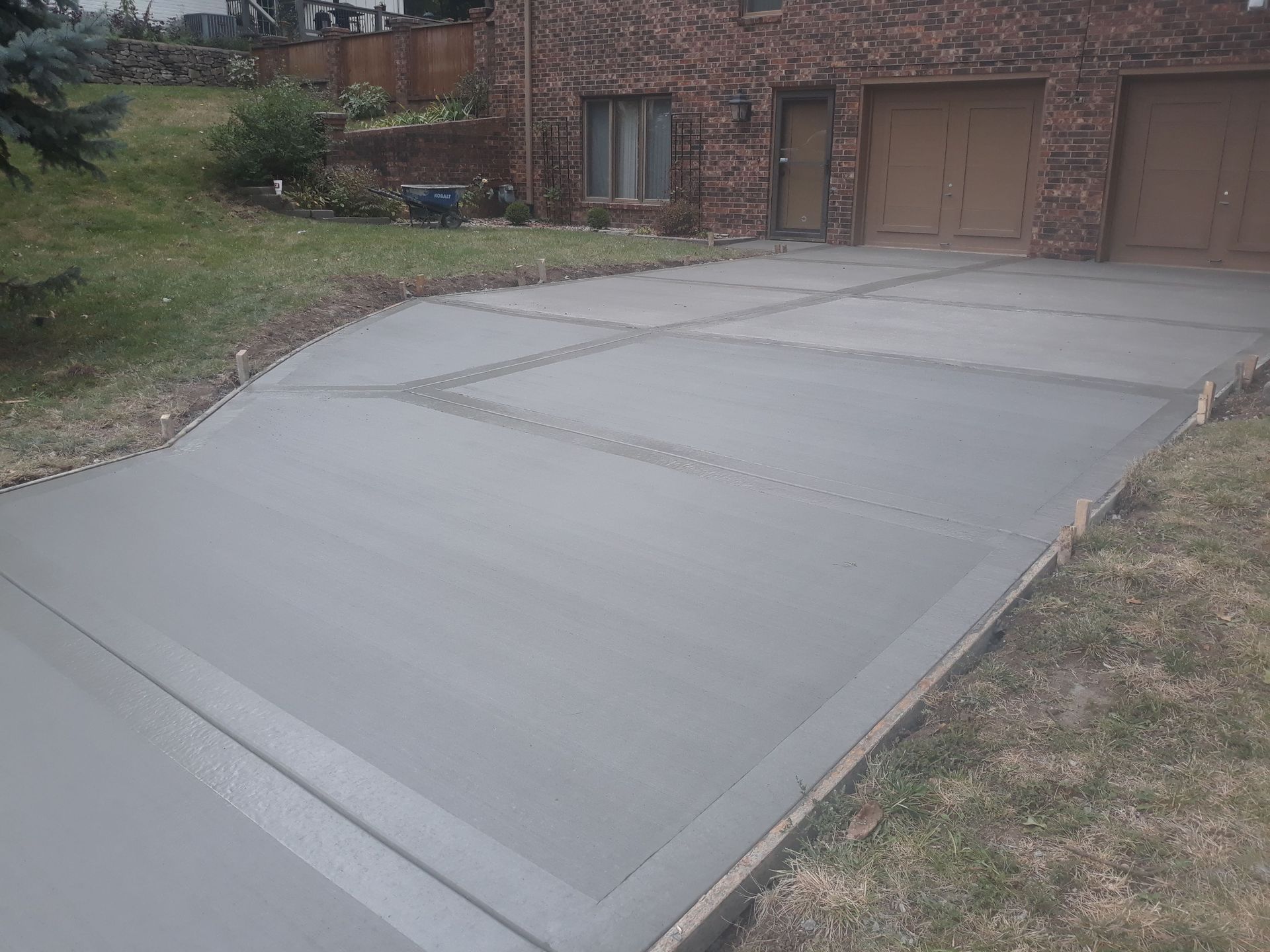 A concrete driveway in front of a brick house.