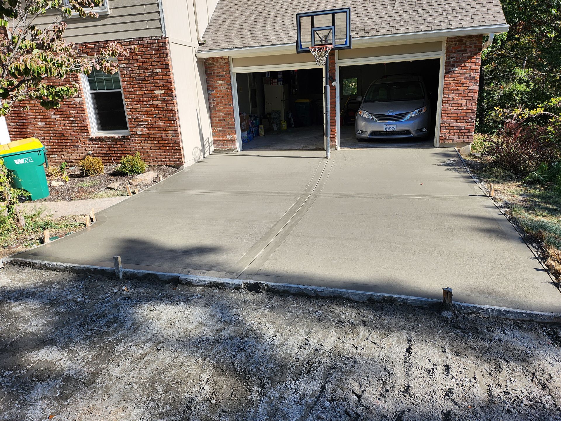 A car is parked in a garage next to a basketball hoop.
