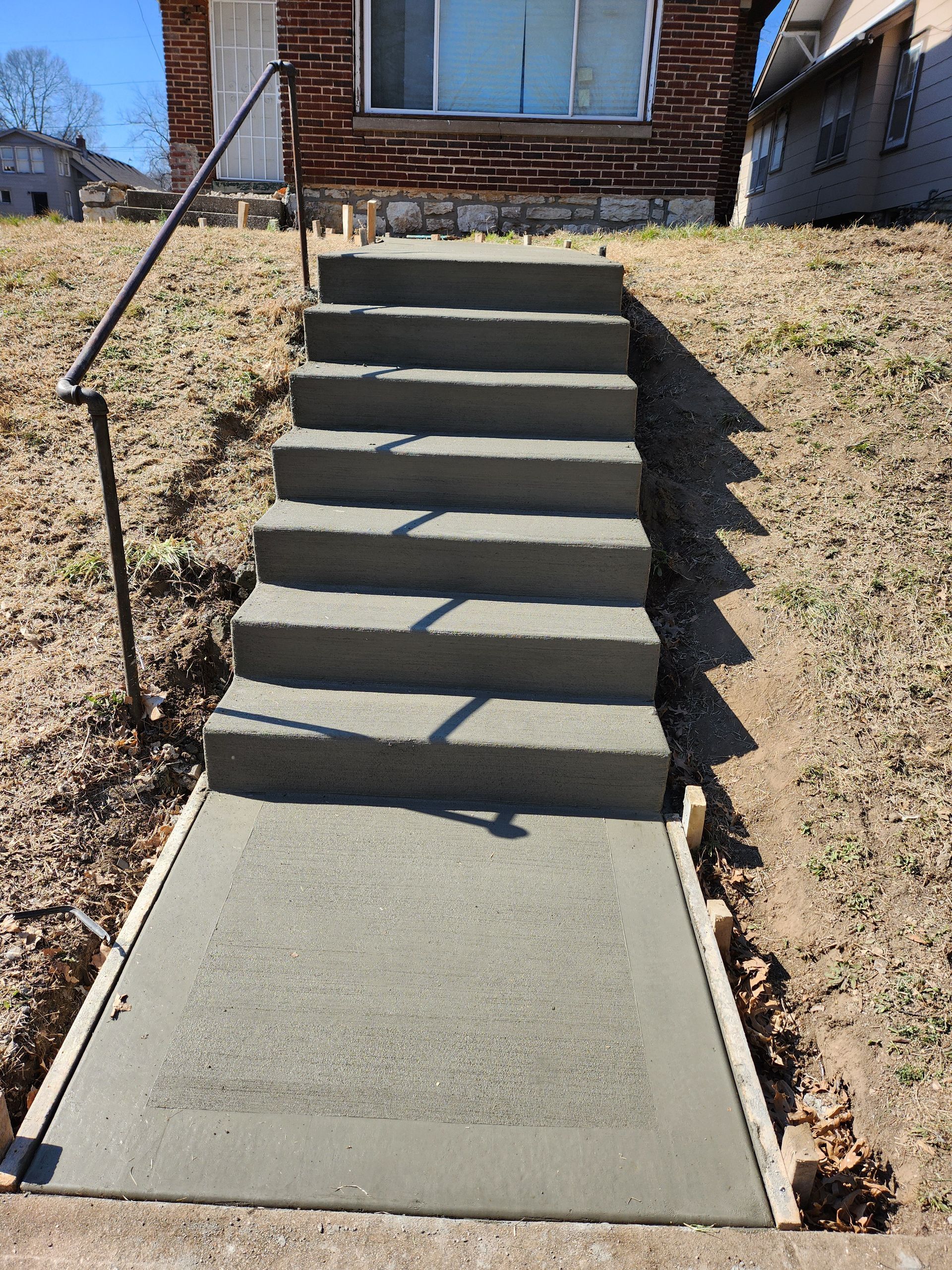 Concrete sidewalk and staircase is being built in front of a house