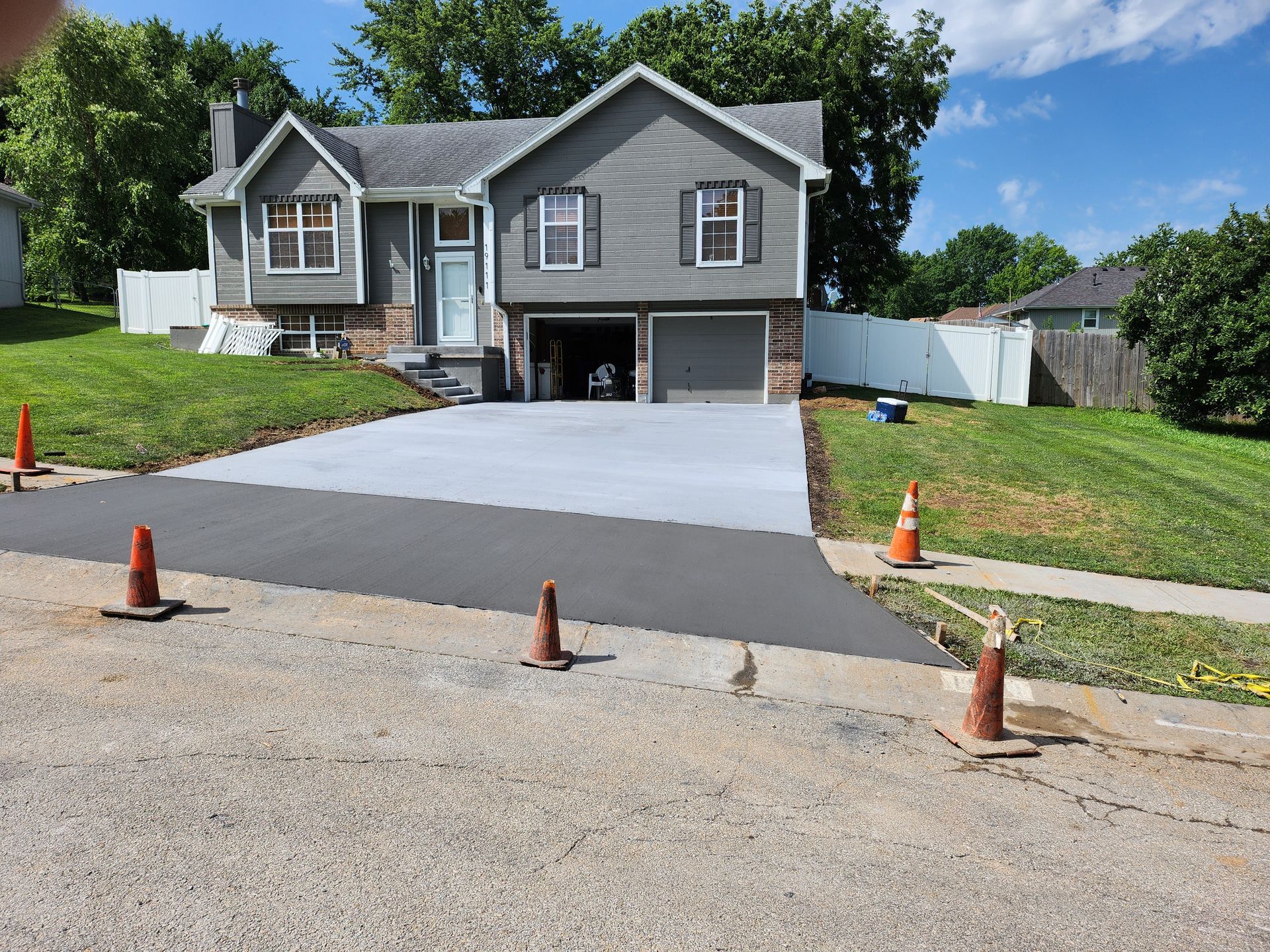 A gray house with a concrete driveway in front of it