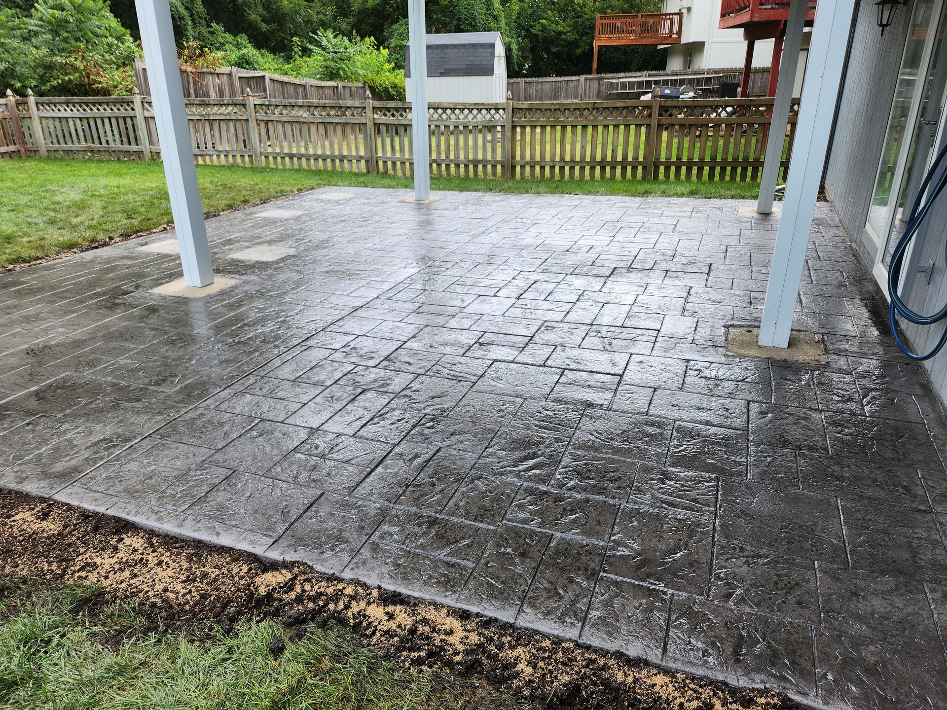 A concrete patio with a wooden fence in the background.