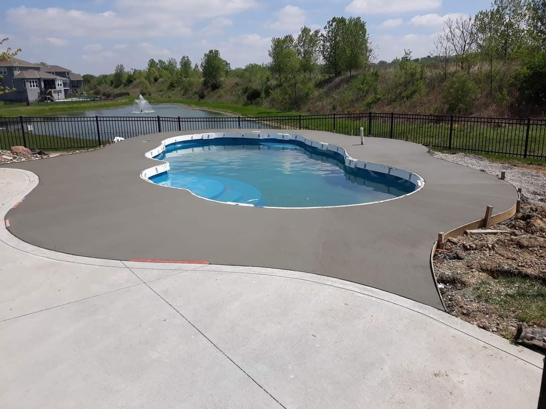 A large swimming pool is surrounded by a concrete patio.