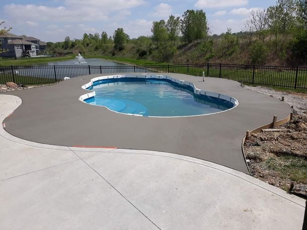 A large swimming pool is surrounded by a concrete patio.