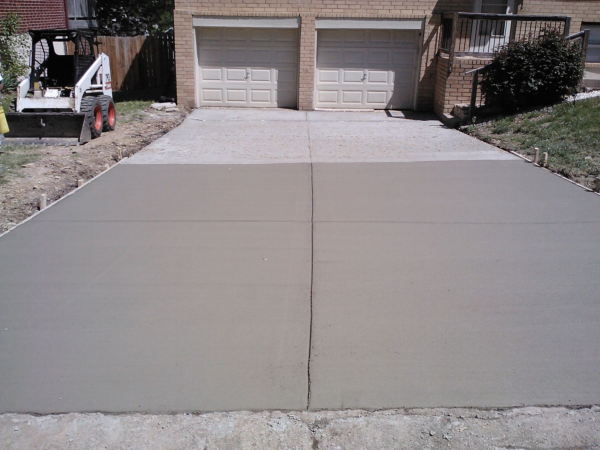 A concrete driveway is being built in front of a house