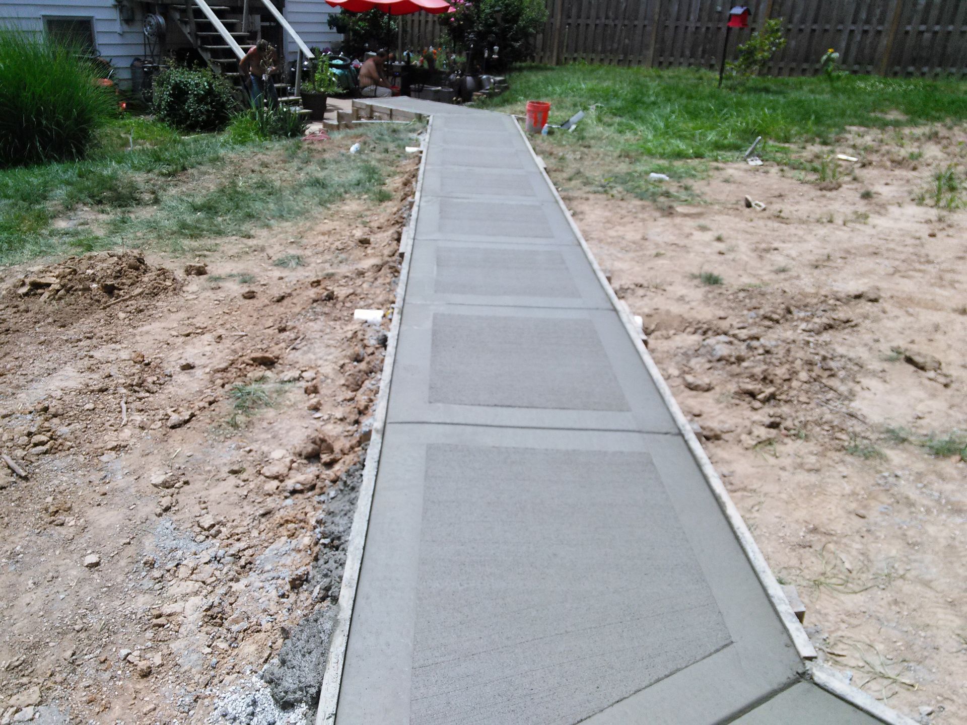 A concrete walkway is being built in a backyard