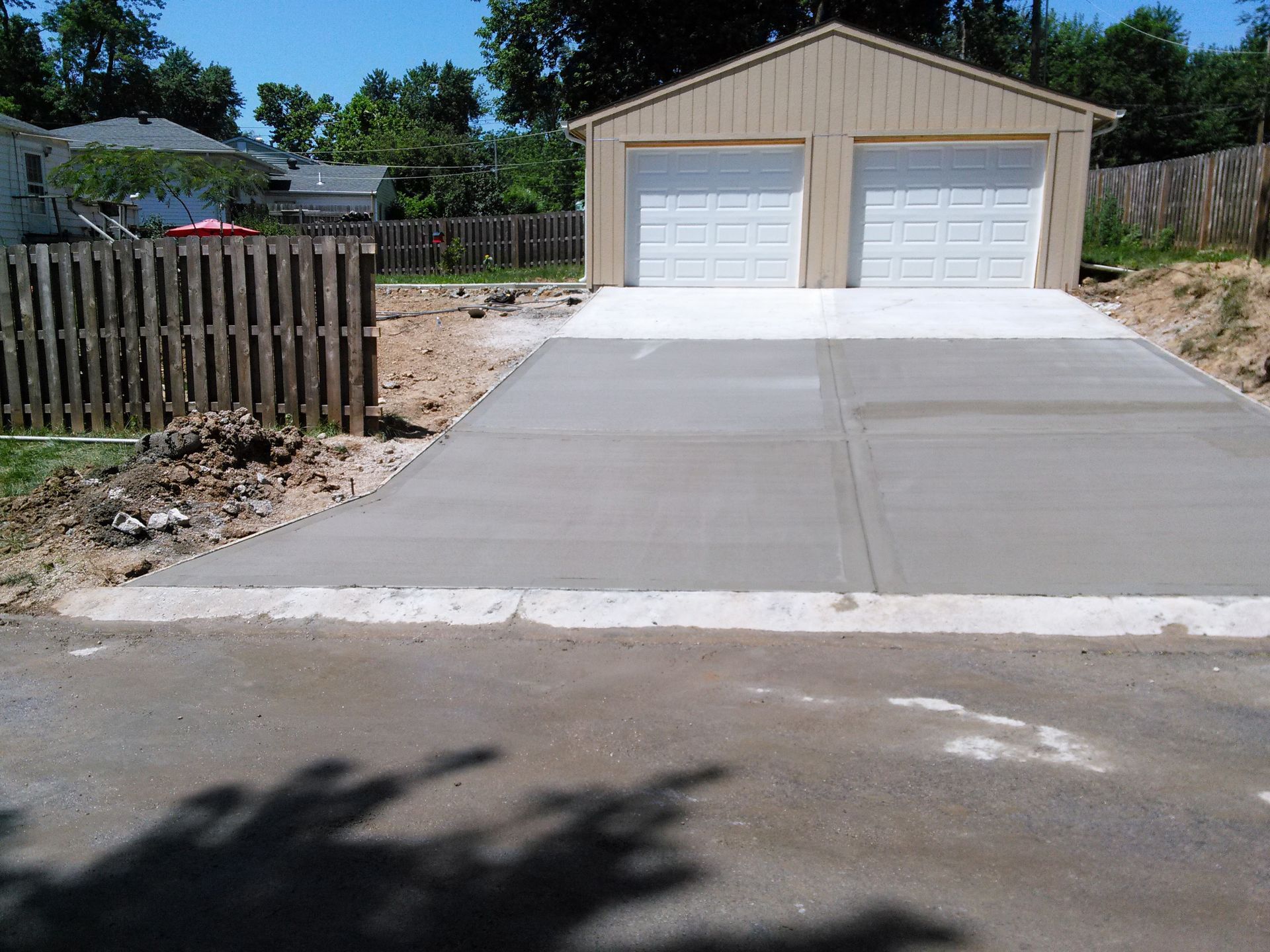 A concrete driveway leading to a garage with two garage doors
