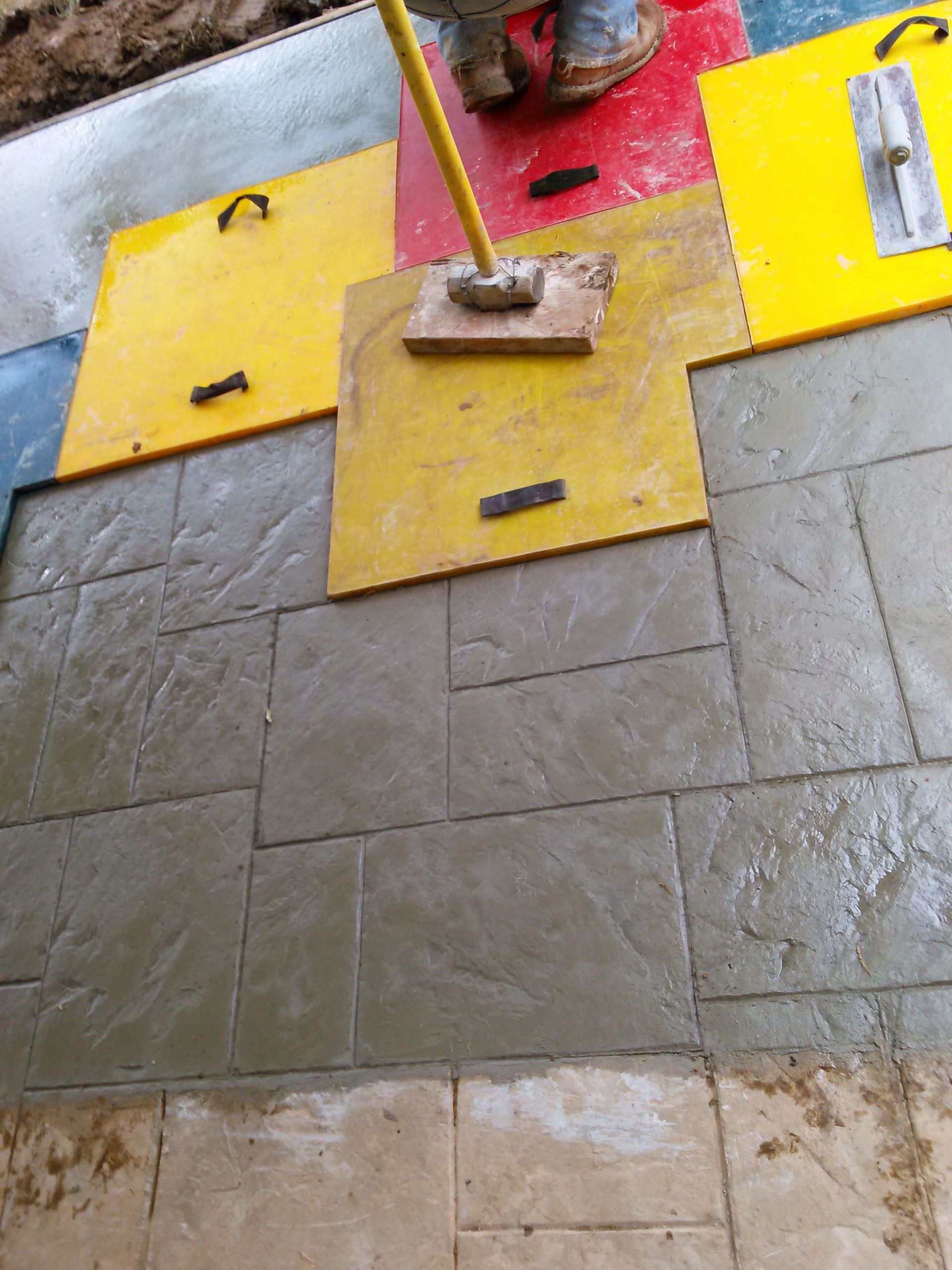 A person is laying concrete on a tiled floor