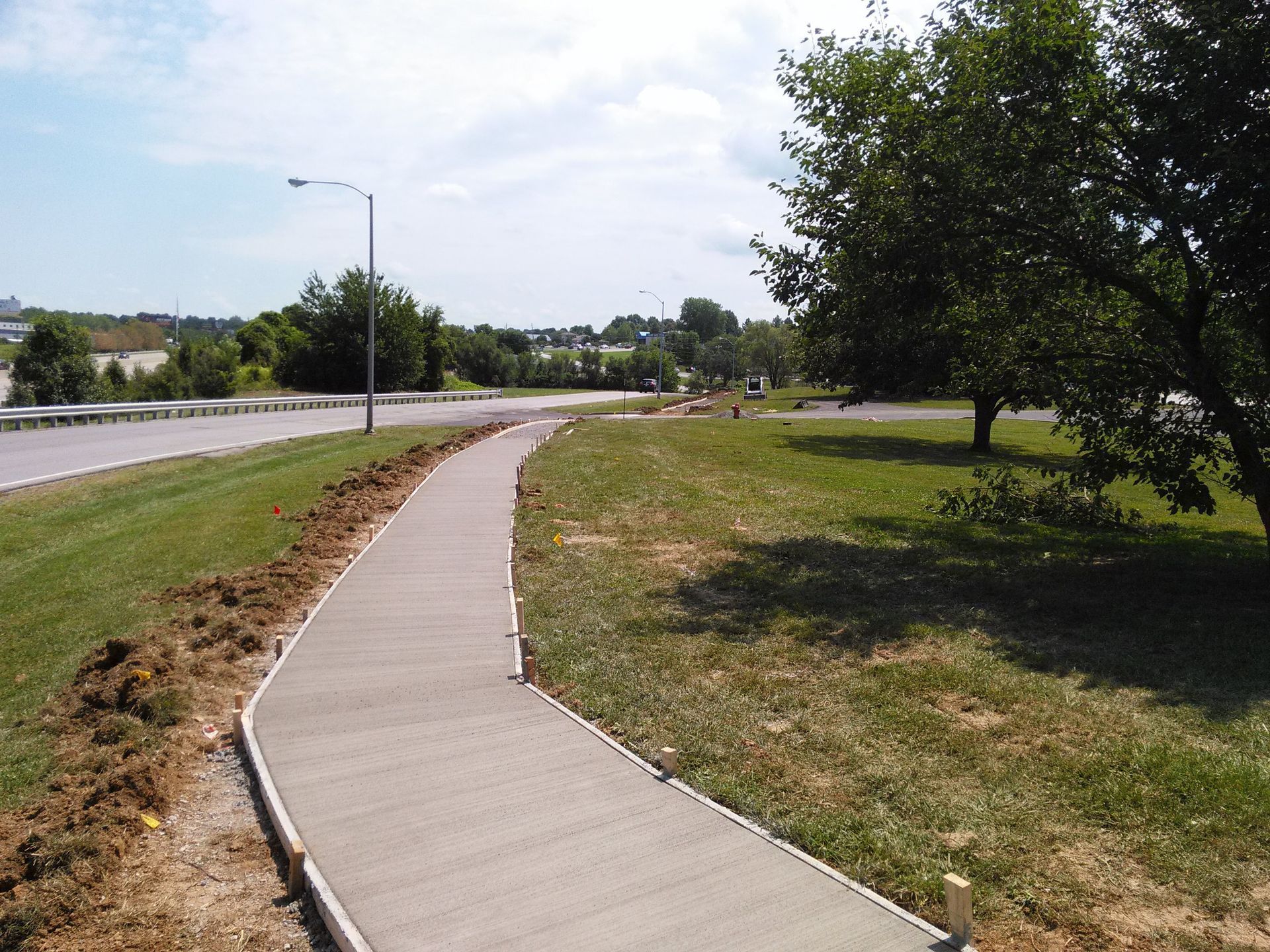 A concrete walkway going through a grassy field