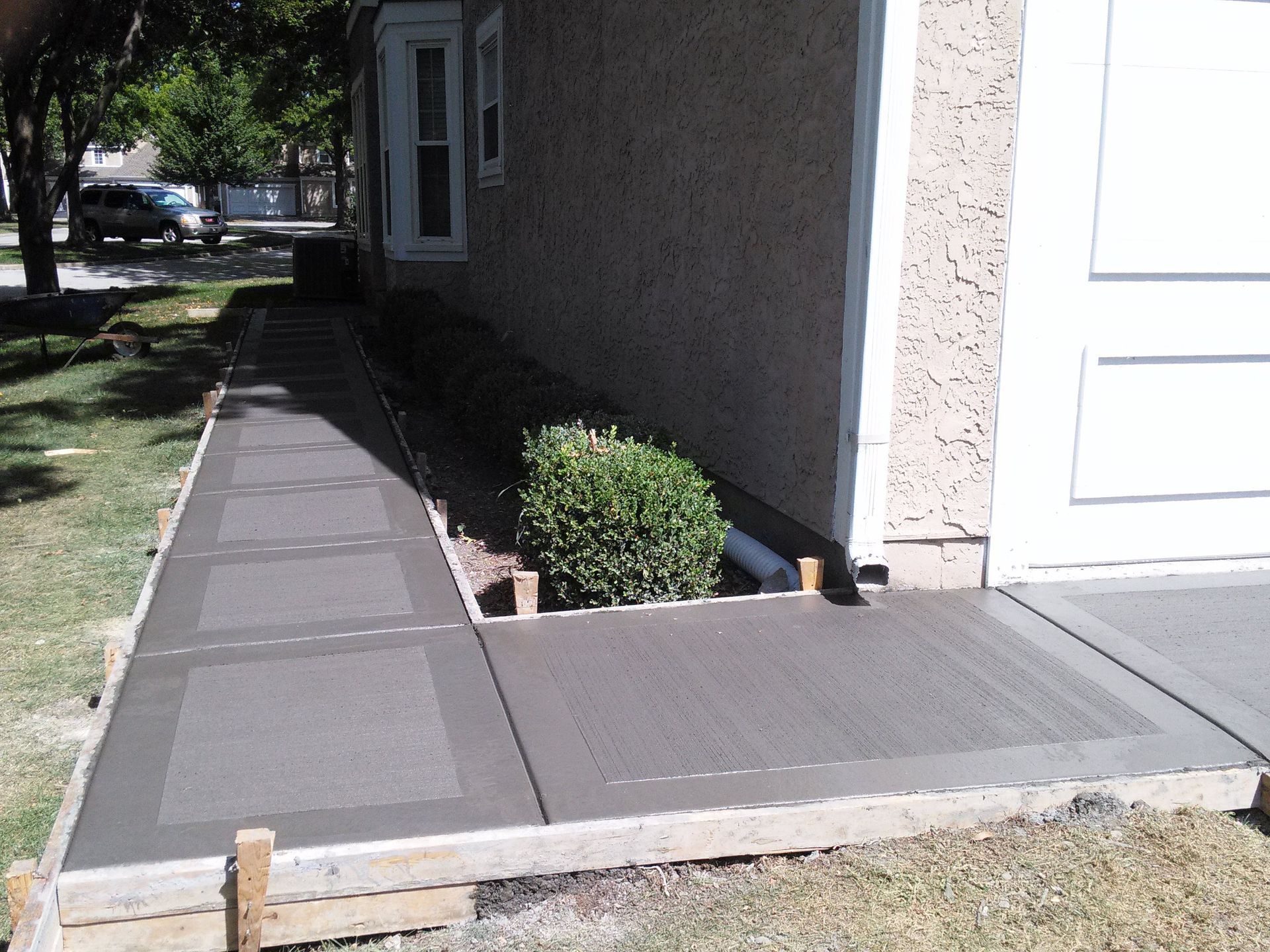 A concrete walkway is being built in front of a house