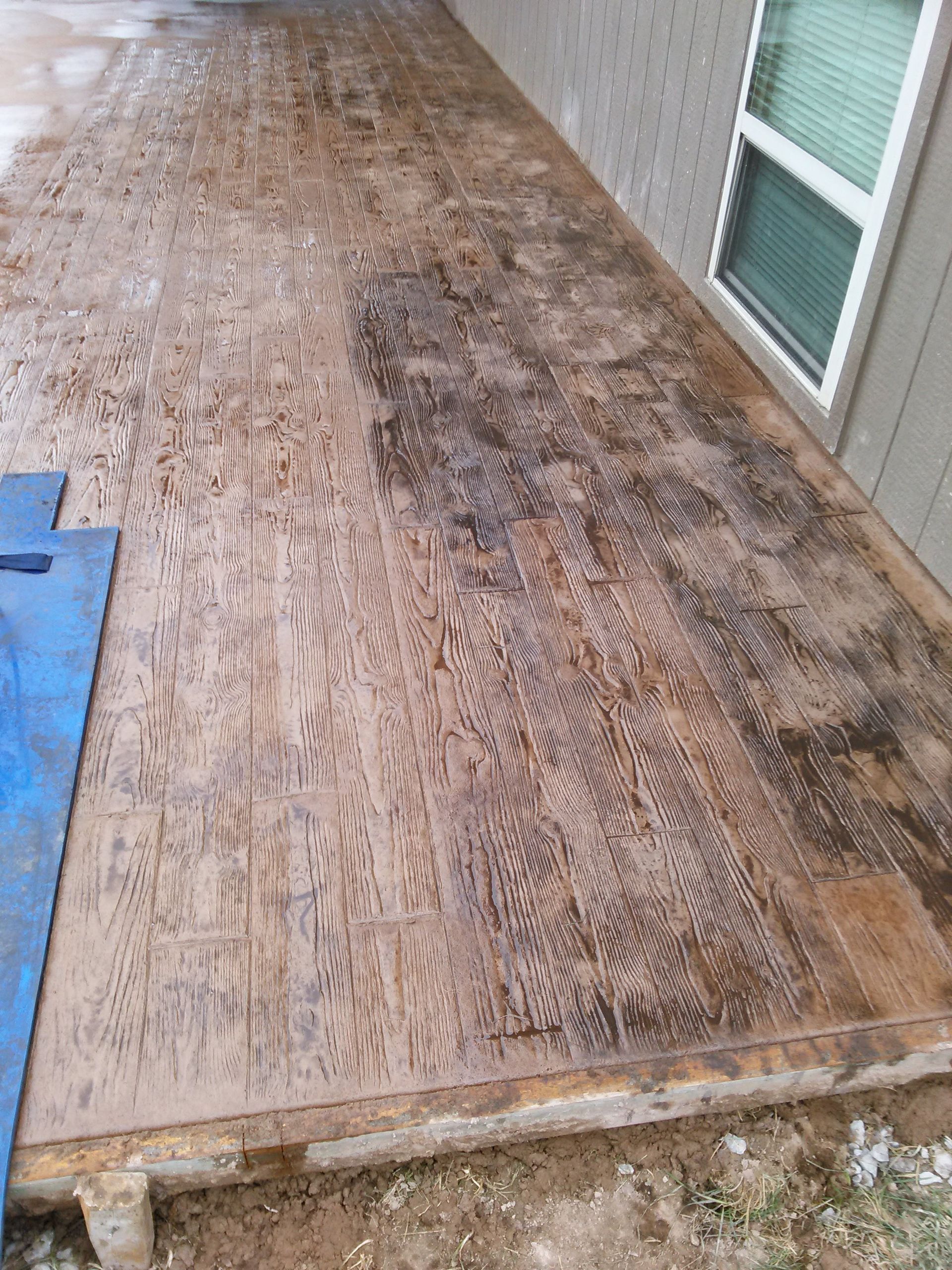 A concrete patio with a blue tarp on the ground in front of a house.