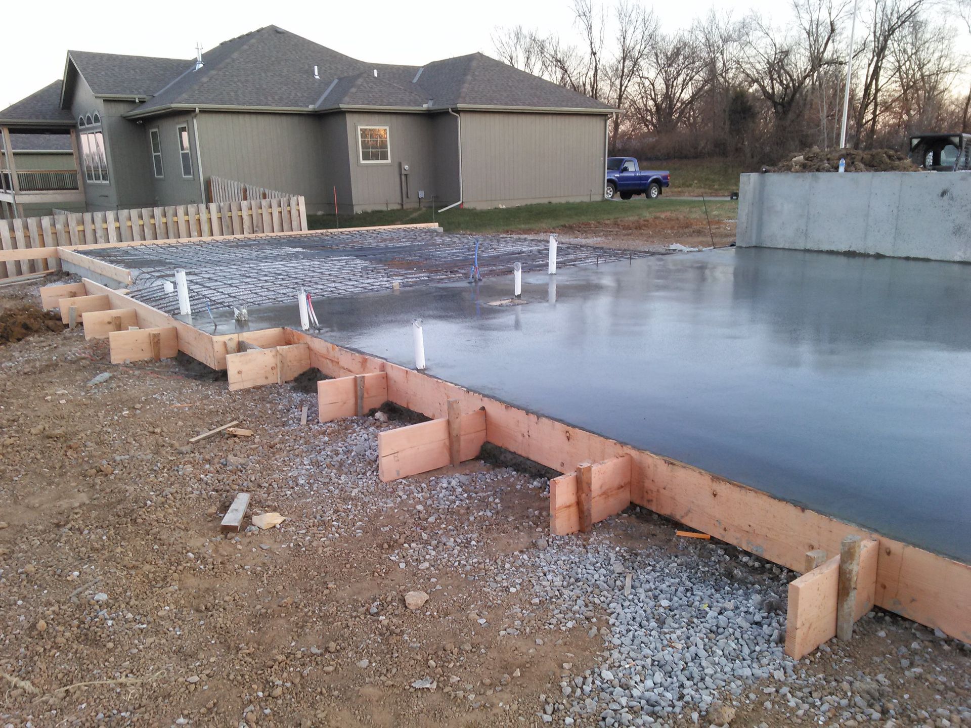 A concrete foundation is being built in front of a house