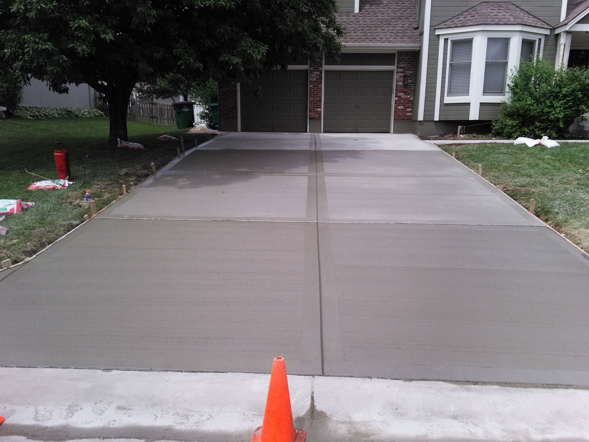 A concrete driveway is being built in front of a house